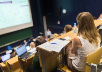 Unterschiede zwischen Uni und Hochschule, Studentinnen und Studenten sitzen im Hörsaal einer Universität, Vorlesung