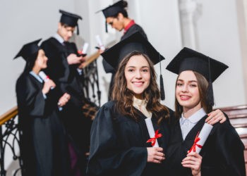 Studierende in Uniform auf Abschlussfeier, Bachelorurkunde in der Hand