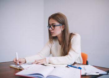 Junge Studentin sitzt am Tisch und lernt, Psychologie Fernstudium